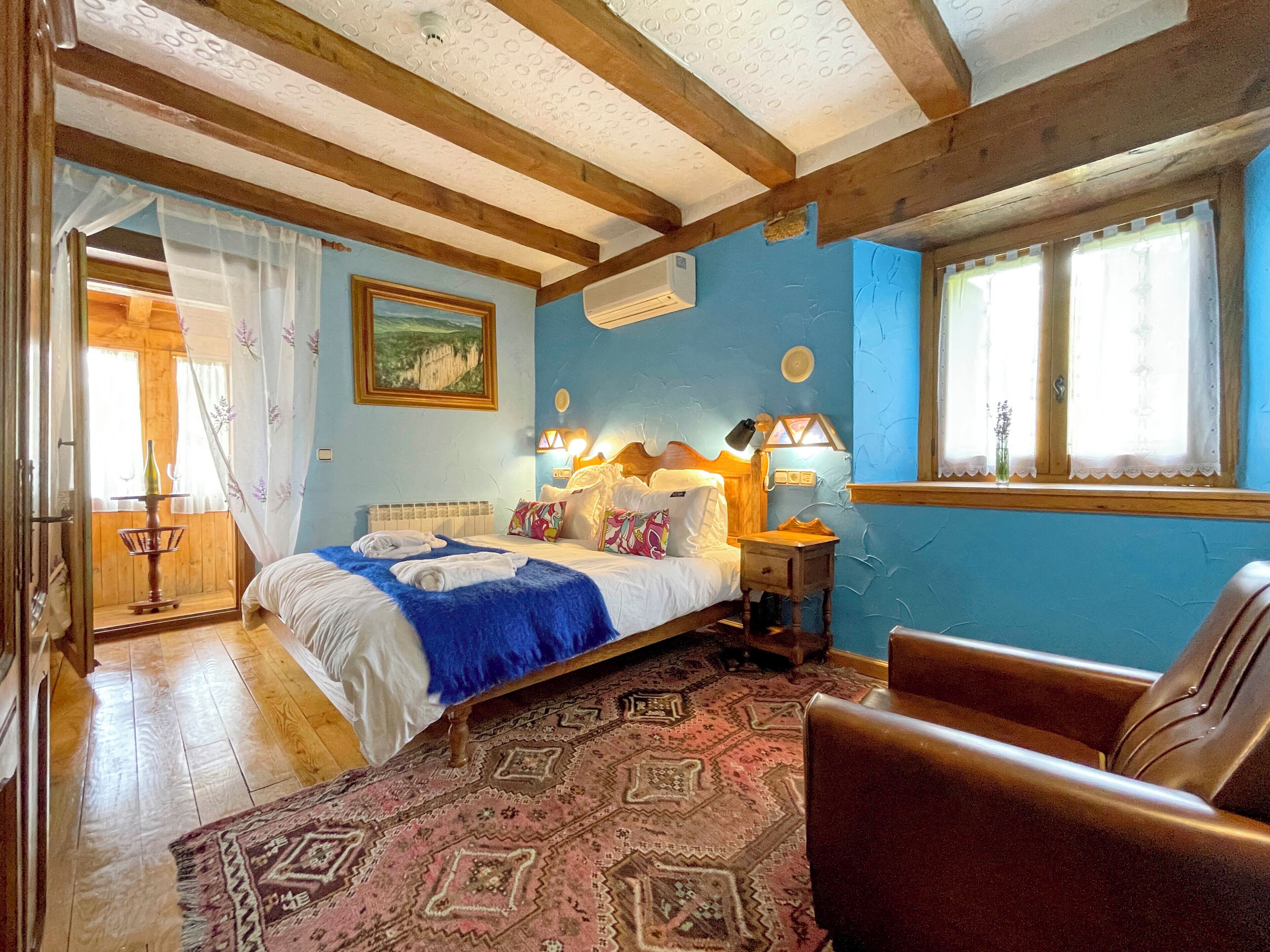A bedroom with a bed, bedside lamps, a window, and a patterned rug.