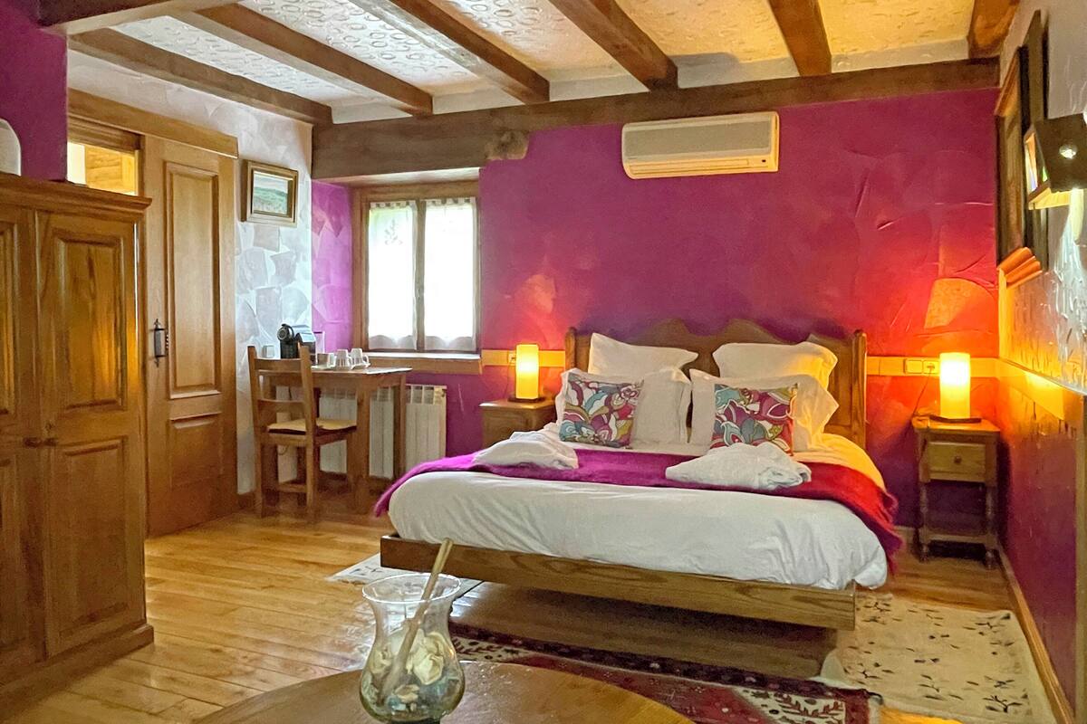 A bedroom with a bed, bedside tables, a desk, and a chair.