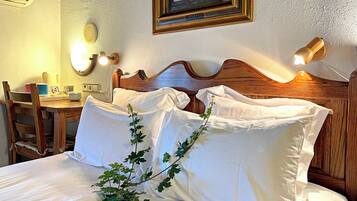 A neatly made bed with white linens, a wooden headboard, and a decorative plant.