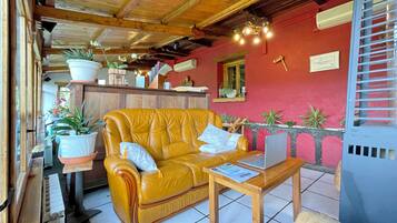 A cozy room with a yellow leather sofa, a wooden table with a laptop, and a red wall with a window.
