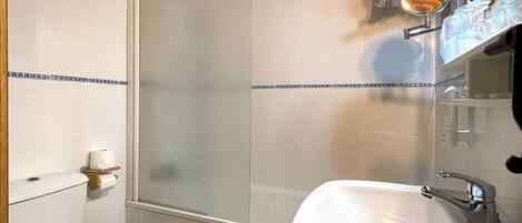 A bathroom with a toilet, sink, and a shower enclosure.