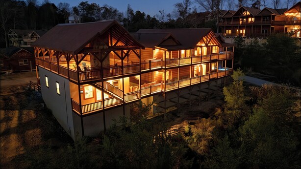 Un lodge in legno a più piani con balconi e una zona esterna coperta, immerso tra gli alberi.