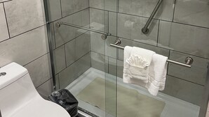 A modern bathroom with a glass-enclosed shower, a white toilet, and a towel rack with a white towel.