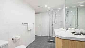 A modern bathroom with a toilet, sink, and shower area.