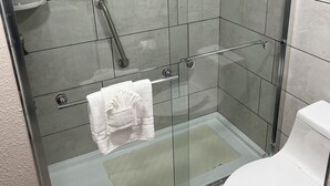 A modern bathroom with a glass-enclosed shower, a white toilet, and a towel rack.
