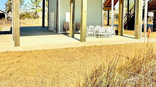 A two-story building with a balcony, wooden ceiling, and a covered patio area with outdoor furniture. - The Bay Stay has boat pier ~ 4 mi. to Beach. Cart into town- Close to Boat ramp  (Bay St. Louis)