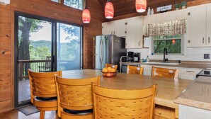 A wooden cabin kitchen with a large dining table, chairs, and a view of the outdoors. - Serene Cabin - Incredible VIEWS, 3 Bedrooms, 3 Bathrooms, Family & Pet-Friendly! (Deep Gap)