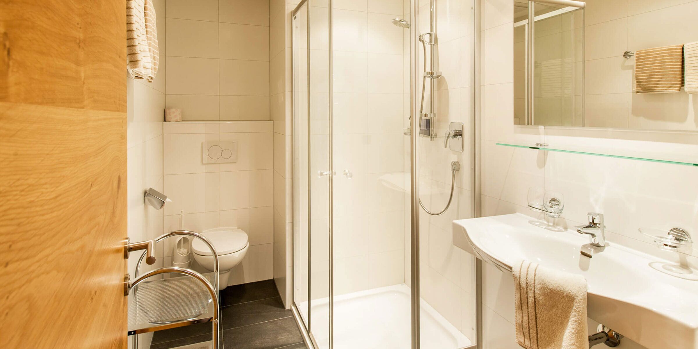 Un bagno moderno con cabina doccia in vetro, un lavandino bianco con piano in vetro e un water.