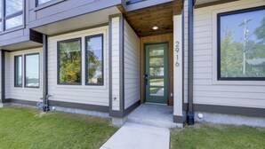 A modern two-story house with a green door, large windows, and a visible address number 2916.