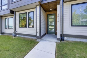 Stylish two-story home with a clean design, featuring a green door and well-manicured lawn.