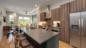 A modern kitchen with a central island, stainless steel appliances, and wooden cabinetry.