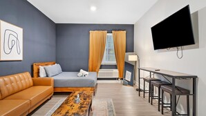Una habitación de hotel moderna con cama, sofá, escritorio y televisor.