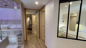 A hotel corridor with a wooden floor, a glass partition on the left, and a mirrored wall on the right. - Chalet Hestia (Font-Romeu-Odeillo-Via)