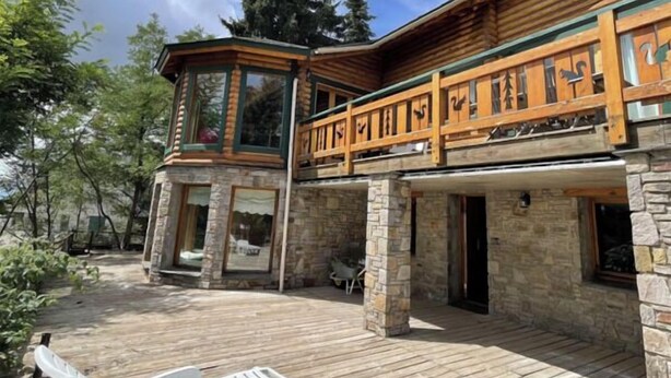 A log cabin with a stone foundation, a wooden deck, and a balcony with decorative railings. - Chalet Hestia (Font-Romeu-Odeillo-Via)