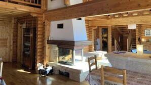 A log cabin interior with a fireplace, wooden beams, and a dining area. - Chalet Hestia (Font-Romeu-Odeillo-Via)