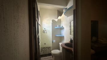 Een smalle gang die uitkomt op een badkamer met toilet, wastafel en handdoekhouder.