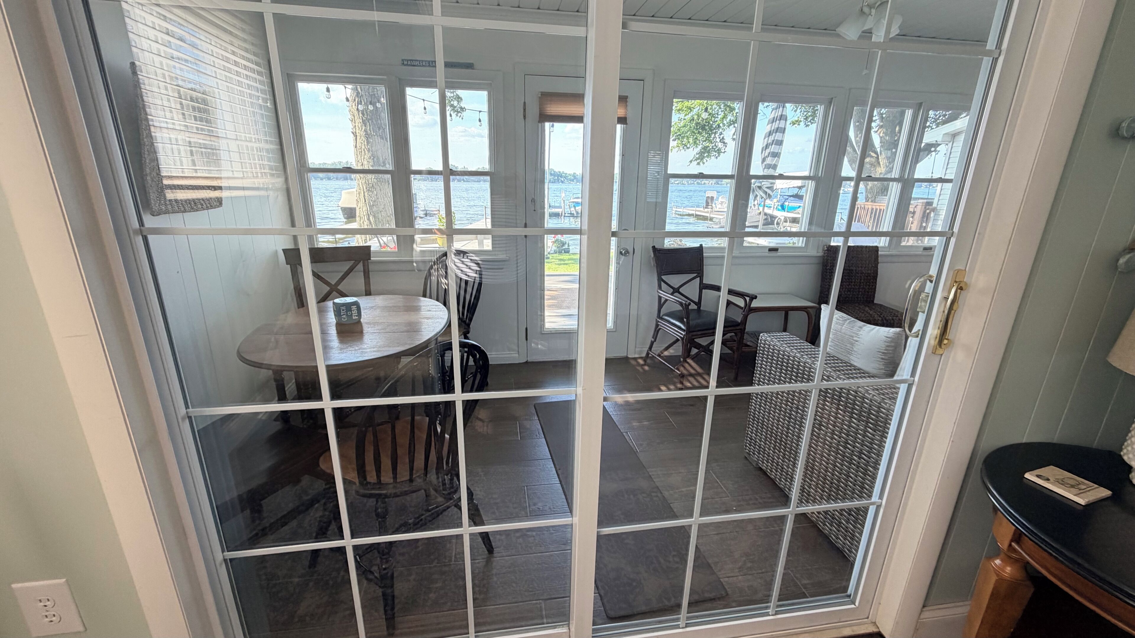 Ein Zimmer mit Blick aufs Wasser, ein Tisch mit Stühlen und ein Korbsessel.