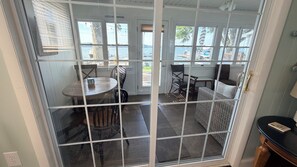 Quarto com vista para a água, uma mesa com cadeiras e um sofá de vime.