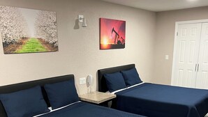 Una camera d'albergo con due letti, un tavolino e opere d'arte alle pareti.