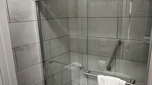 Un bagno moderno con doccia vetro-muraria, un water bianco e un porta asciugamani.
