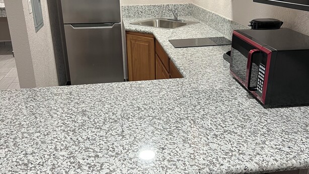 Una cucina con piani di lavoro in granito, elettrodomestici in acciaio inossidabile e mobili in legno.