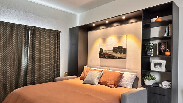Une chambre moderne avec un grand lit, une bibliothèque intégrée et une œuvre d’art accrochée au mur.
