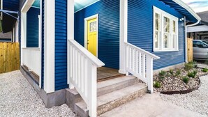 Een blauw huis met een gele deur, witte leuningen en een nummer 414.