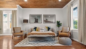 Een slaapkamer met een bed, twee stoelen, een lamp en twee foto’s in lijsten aan de muur.