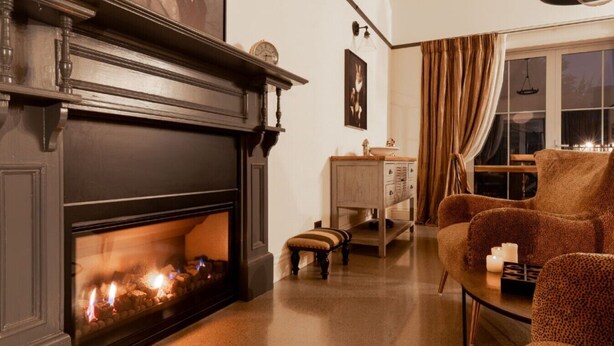 Una habitación con chimenea, un sofá, una mesa con velas y una ventana con cortinas.
