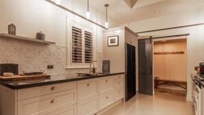 Una cocina con un refrigerador negro, una ventana con persianas y un lavamanos.