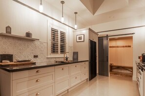 A kitchen with a black refrigerator, a window with blinds, and a sink.