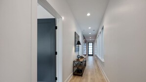 A hallway with a dark door, a desk with a lamp, and a window at the end. - `The Ryman` 4BR Haven with Scenic Rooftop (Nashville)
