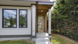 A modern two-story house with a front door, large windows, and a small porch. - `The Ryman` 4BR Haven with Scenic Rooftop (Nashville)