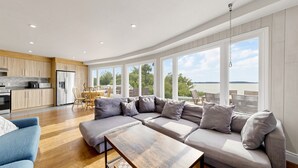 Ein modernes Wohnzimmer mit einer Eckcouch, einem Holztisch und Blick ins Freie.