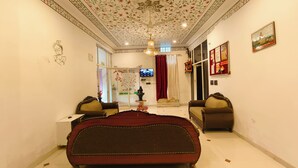 Une chambre à coucher avec un grand lit, deux fauteuils, une télévision et un plafond décoratif.