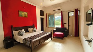 Une chambre à coucher avec un lit, une chaise, un téléviseur et une fenêtre avec des rideaux.
