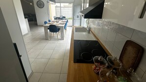 A modern kitchen with a dining area, featuring a large table, chairs, and a built-in stove.