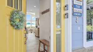 A yellow door with a wreath, a bench, and a sign saying "HOME IS WHERE THE ANCHOR DROPS". - Spacious home w full Kachemak Bay views (Homer)