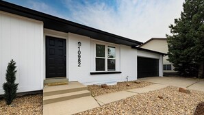 A residential house with a black door, white siding, and a driveway with gravel. - 5BD I Game Room I Backyard & BBQ I 20 Mins to DEN (Thornton)