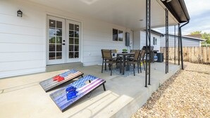 A covered patio with a table and chairs, a small table with a plant, and two American flag-themed lounge chairs. - 5BD I Game Room I Backyard & BBQ I 20 Mins to DEN (Thornton)