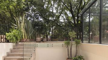 A staircase leading to a balcony with potted plants and a glass railing.