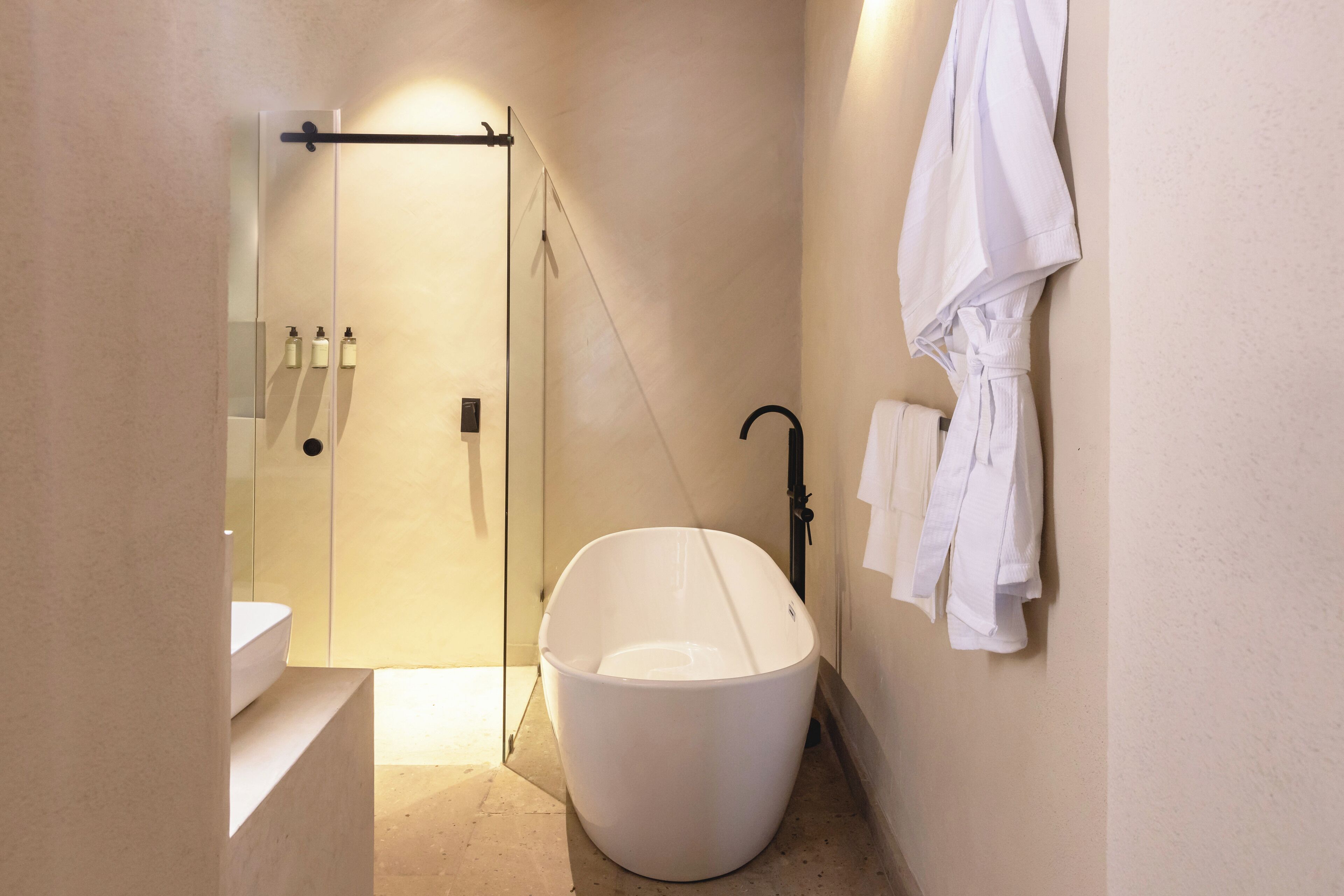 A modern bathroom with a freestanding bathtub, a glass shower enclosure, and a towel rack with towels.