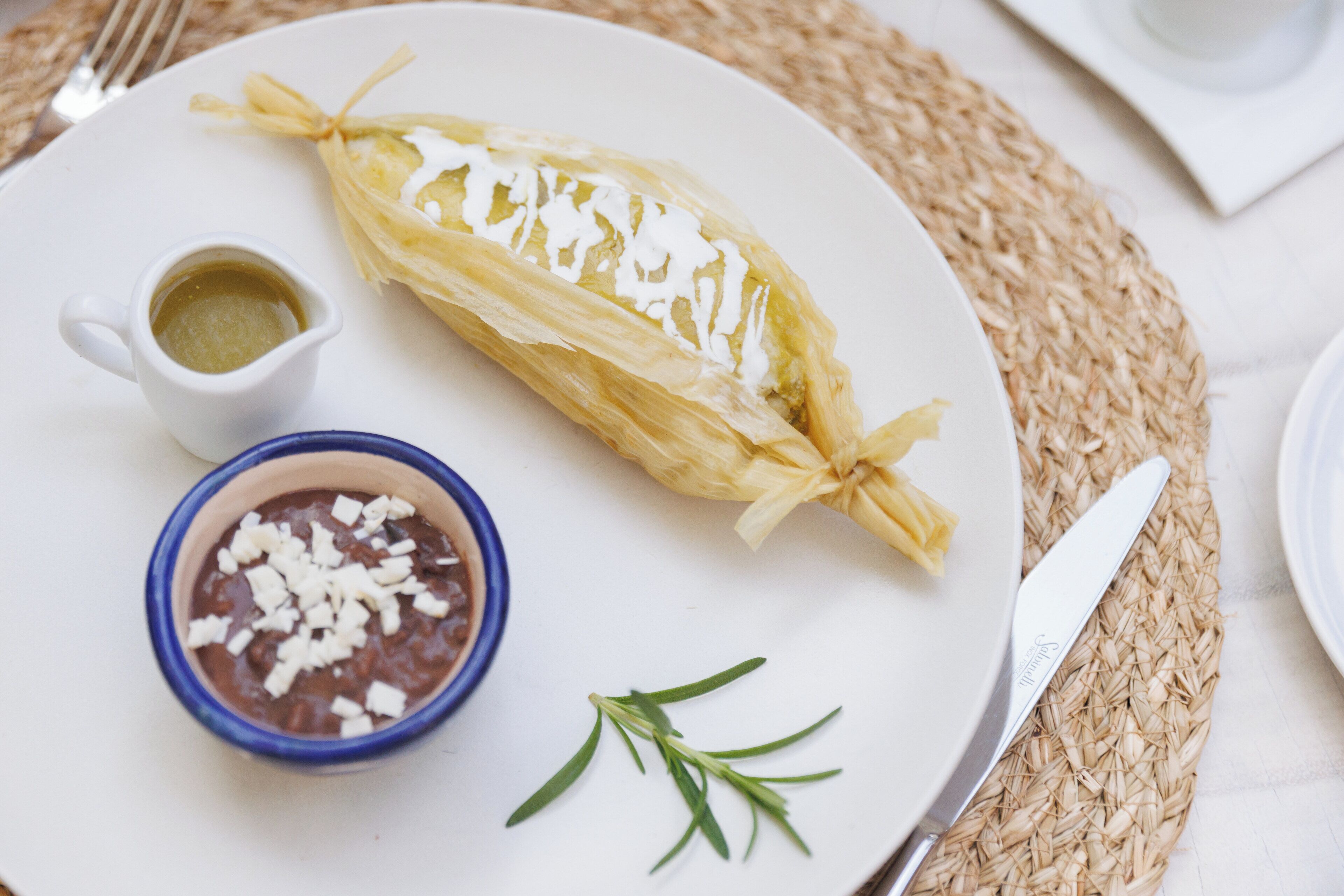 A plate with a wrapped food item, a small bowl of chocolate, and a small cup of sauce.
