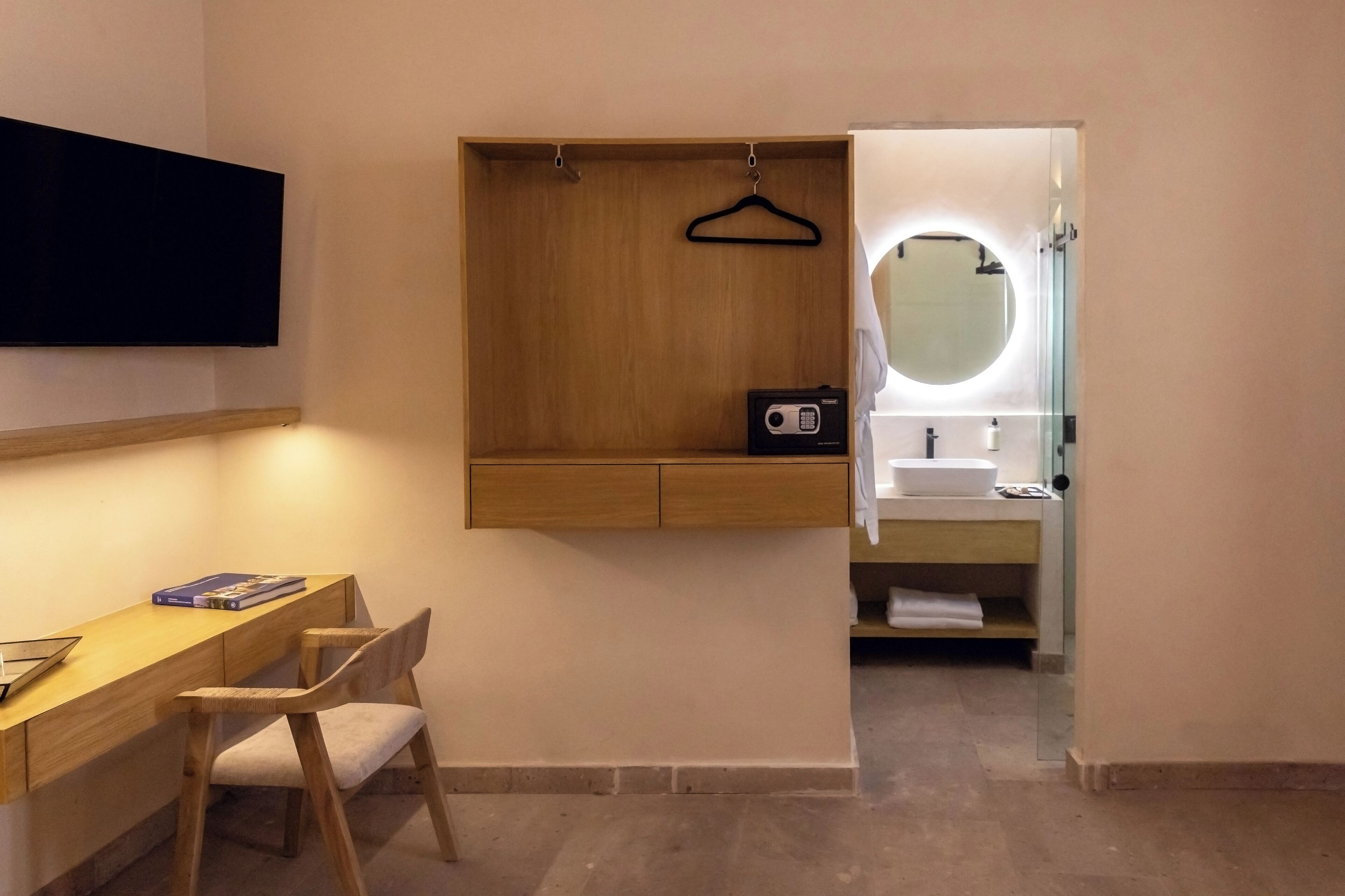 A modern bathroom with a wooden vanity, a round mirror, and a sink.