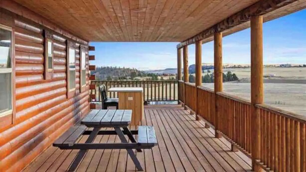 Eine Holzterrasse mit Picknicktisch und kleinem Tisch, mit Blick auf eine schöne Landschaft.