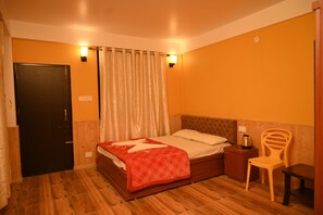 A bedroom with a wooden bed, a nightstand, a chair, and a door. - Bayaroo Stay Lamahatta (Darjeeling)