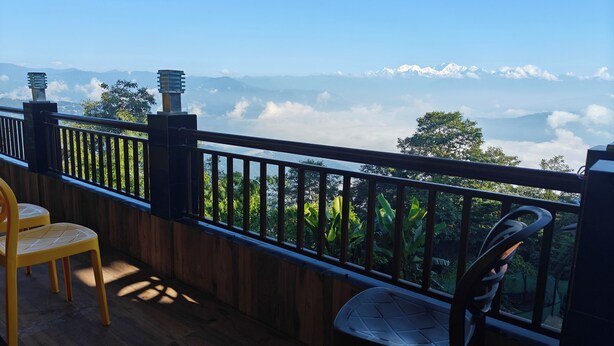 A balcony with a view of mountains and clouds. - Bayaroo Stay Lamahatta (Darjeeling)