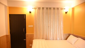 A hotel room with a bed, a door, and a curtain. - Bayaroo Stay Lamahatta (Darjeeling)