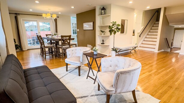 A spacious living area with a dark sofa, white armchairs, and a dining table. - Grand Lakeview Retreat Near Town • Game Rm • 4BR (Princeton)