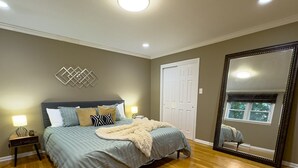 A bedroom with a bed, bedside lamps, a large mirror, and a door. - Grand Lakeview Retreat Near Town • Game Rm • 4BR (Princeton)